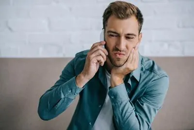 man scheduling an emergency dental appointment due to tooth pain