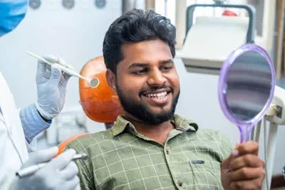 man smiling in the mirror after his restorative dentistry procedure